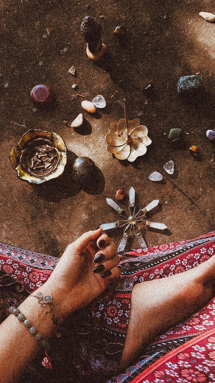 brand-03 A woman's hand in a spiritual ritual with crystals, incense, and natural elements.