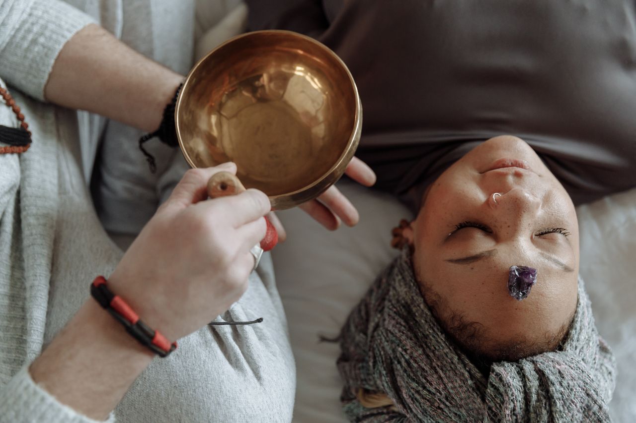 our-story Woman receiving healing therapy with a Tibetan singing bowl placed during meditation.